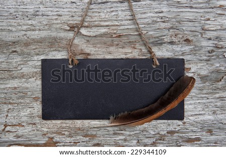 Chalkboard with feather on old wood background