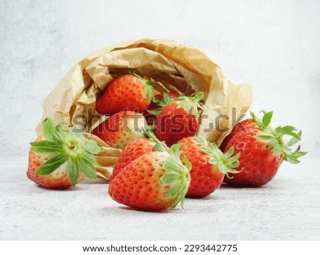 Natural and delicious strawberries on a stone base and inside a kraft paper bag.