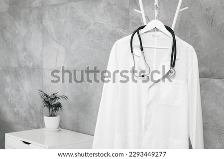 White doctor's gown and stethoscope on rack in clinic Royalty-Free Stock Photo #2293449277