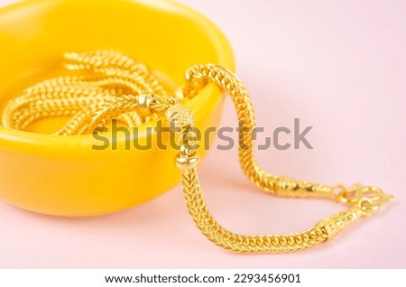 Gold necklace on pink background.