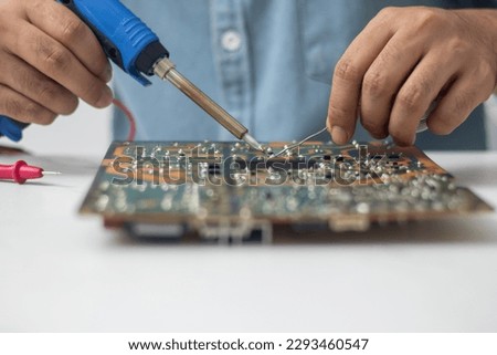 Technician using a soldering iron to repair a circuit board Royalty-Free Stock Photo #2293460547