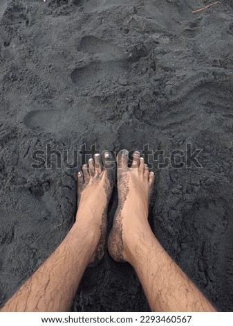feet on black sand beach photographed from above