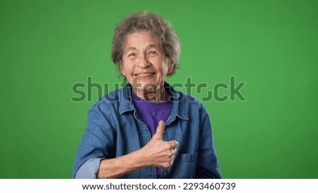 Portrait of excited, surprised elderly senior old woman with wrinkled skin saying WOW smiling giving a thumbs up. Grey hair smiling isolated on green screen background studio