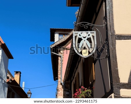 An old barbershop, with a vintage scissors sign and traditional tools above the entrance. A colorful design stylishly decorates the building exterior - clear blue sky in background