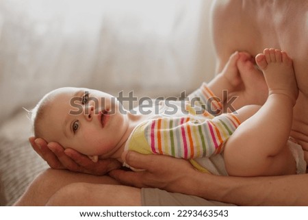 Baby in pajamas lies in hands of father