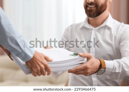 Woman giving documents to colleague in office, closeup