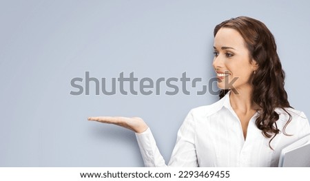 Profile side portrait image of beautiful young business woman showing, giving, holding, advertising, isolated on grey background. Businesswoman, executive office worker, teacher gesturing.