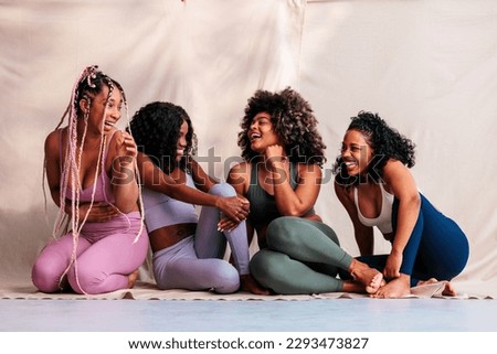 A group of elated diverse friends in activewear are indoors sitting  on the floor and smiling. Royalty-Free Stock Photo #2293473827