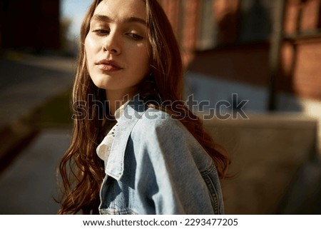 Youth street fashion, womenswear, denim outfit concept. Closeup portrait of lovely caucasian teen girl in trendy clothes outdoor at big city streets, looking aside with thoughtful facial expression Royalty-Free Stock Photo #2293477205