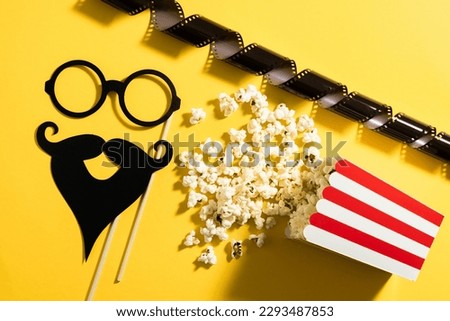 Popcorn bucket and photo booth prop for movie party on yellow background.