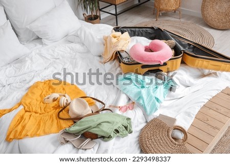 Open suitcase with beach accessories on bed in room