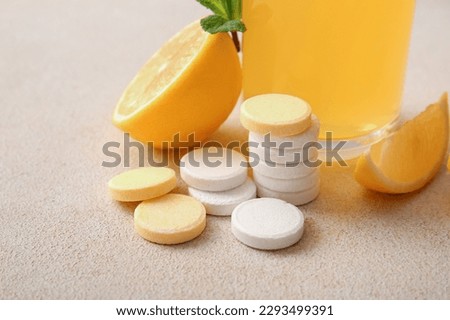 Vitamin C effervescent tablets and lemons on beige grunge table Royalty-Free Stock Photo #2293499391