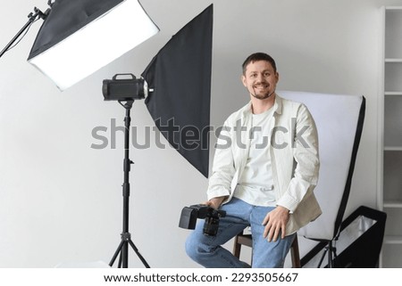 Male photographer with professional camera sitting in studio