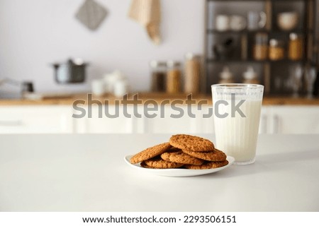 Plate with cookies and glass of milk on table in modern kitchen Royalty-Free Stock Photo #2293506151
