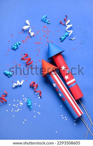 Firework rockets, serpentine and confetti for Independence Day on blue background Royalty-Free Stock Photo #2293508605