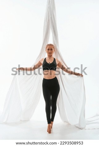 Young beautiful woman doing fly yoga against white background.