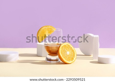 Glass of rum with orange slices, ice cubes and plaster figures on colorful background