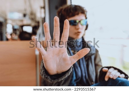 young teen girl in sunglasses showing stop hand in public transport, stop gesture. Childhood problem, voice concept. makes hand gesture to prohibit taking pictures on public transport