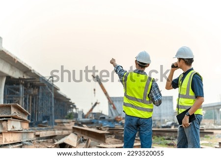 Architect and Civil Engineer checking work with walkie-talkie for communication to management team in the construction site. Royalty-Free Stock Photo #2293520055