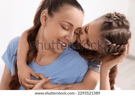 Cute daughter kissing and hugging her mom indoors
