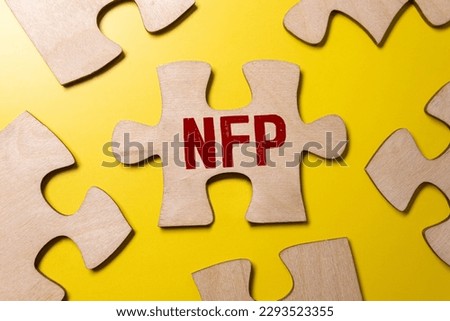 Selective focus of pens, clock, money banknote and notebook written with text NFP stands for Nonfarm payrolls. Business concept.