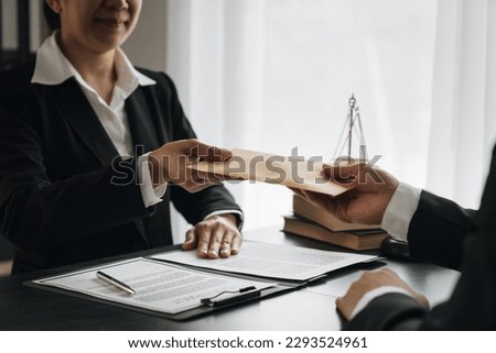 Businessman, investor offering bribe Handing a brown money envelope to a female lawyer or legal counsel to help with a lawsuit, signing documents. Business contract, bribery, fraud concept.