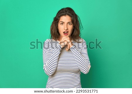 Young caucasian woman isolated praying for luck, amazed and opening mouth looking to front.