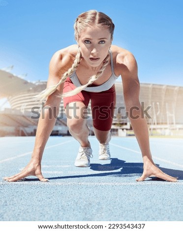 Serious female athlete at the starting line in a track race competition at the stadium. Fit sportswoman mentally and physically prepared to start running at the sprint line or starting block Royalty-Free Stock Photo #2293543437