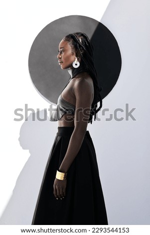 Fierce and fabulous. Shot of an attractive young woman posing in a black outfit against a wall with a circle on it. Royalty-Free Stock Photo #2293544153