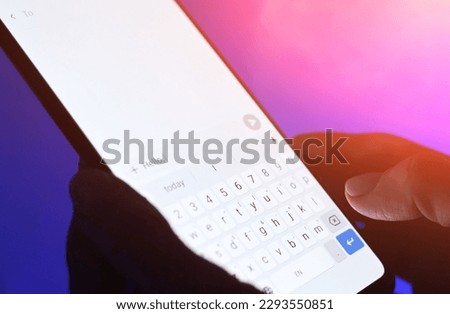 Girl typing message on a smartphone against blue background. Close up viwe of white sceen.
