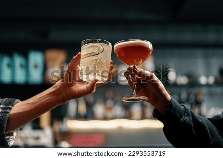 Close up of two people cheering cocktails in bar or disco club drinks and cocktails concept Royalty-Free Stock Photo #2293553719