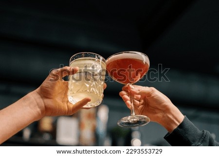 Close up of two people cheering cocktails in bar or disco club drinks and cocktails concept Royalty-Free Stock Photo #2293553729