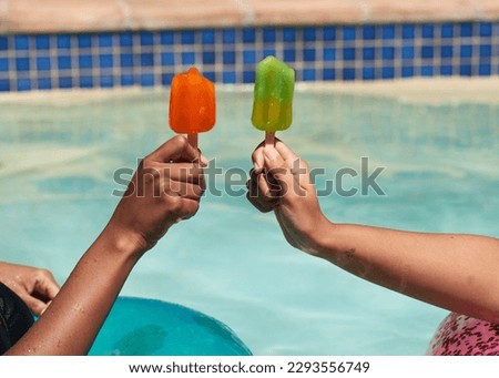 Close up of friends holding ice lolly popsicles in the swimming pool, beat heat Royalty-Free Stock Photo #2293556749