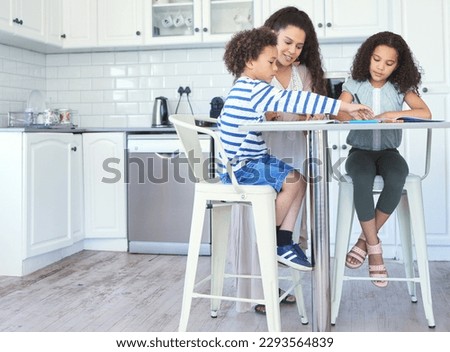 Moms invested in our education. Shot of a mother helping her kids with homework at the kitchen table.