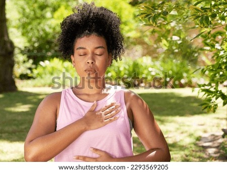 Young mutli-ethnic woman practices deep belly breathing, meditation in park Royalty-Free Stock Photo #2293569205