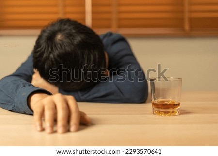 Depressed young Asian man addicted feeling bad drinking whiskey alone at home, stressed frustrated lonely drinking alcohol suffers from problematic liquor, alcoholism, life and family problems Royalty-Free Stock Photo #2293570641