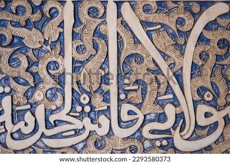 Details of stucco decoration with an Arabic writings painted in blue on the Palaces walls in Alhambra complex, Granada, Andalusia, Spain. 
