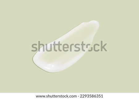 The flowing cream on a green background. Smudged flowing smear of cosmetic cream.