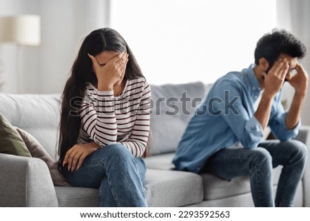 Unhappy young middle eastern couple have quarrel at home, depressed upset man and woman in casual sitting on couch, touching their heads, experiencing difficulties in marriage, copy space Royalty-Free Stock Photo #2293592563