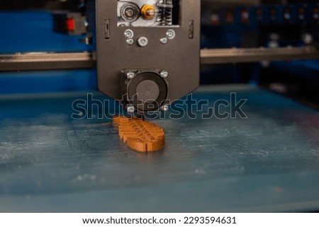 Automatic three dimensional printer machine printing brown plastic model at modern technology exhibition - close up. 3D printing, futuristic, equipment, prototype, manufacturing and production concept Royalty-Free Stock Photo #2293594631