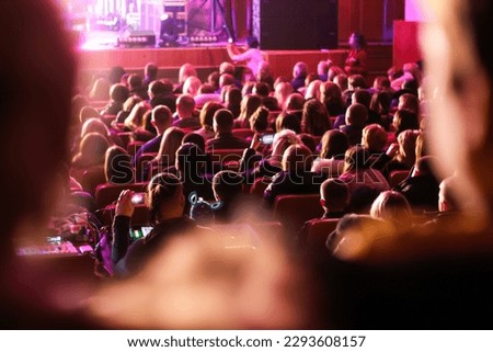 Spectators sit in the hall and watch a concert. People in the auditorium watching the performance. Theater audience. Music concert or festival. Out of focus. Royalty-Free Stock Photo #2293608157