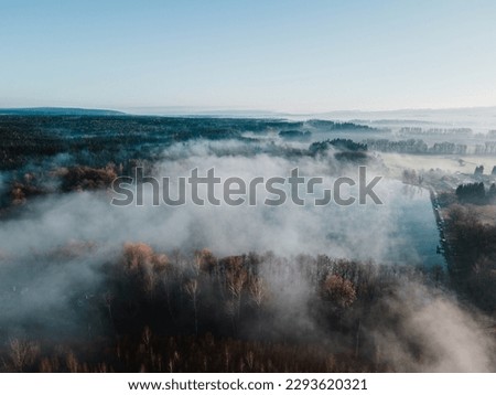 Atmospheric foggy lake with forest during spring sunrise. Svitavy, Czech republic.