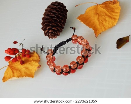 Orange friendship bracelet and leafs. Hippie orange bracelet on a white