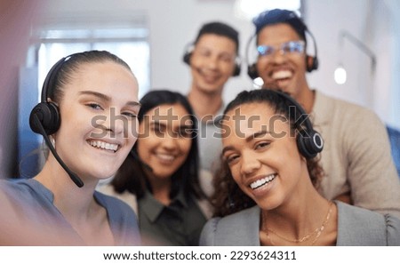 Were all eager to answer your calls. Portrait of a group of call centre agents taking selfies in an office.