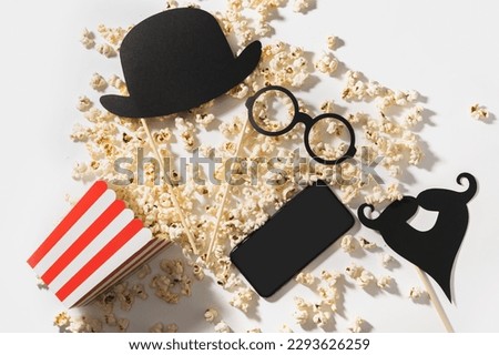 Delicious popcorn, party props and smartphone with blank screen for your design.