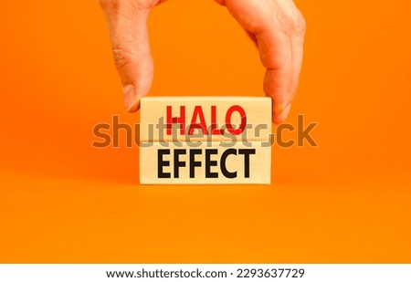 Halo effect and psychological symbol. Concept words Halo effect on beautiful wooden block. Beautiful orange background. Businessman hand. Business psychological and Halo effect concept. Copy space.