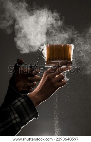 wonderful view on vintage talcum brush and scissors in male hands and talcum powder around in the air. Barber professional tools. Barber shop. Royalty-Free Stock Photo #2293640597