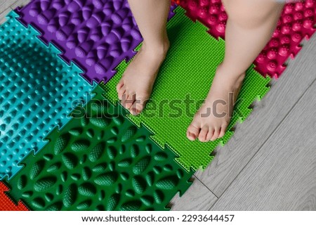 The child walks on an orthopedic massage foot mat with different stiffness and texture.Massage effect on the nerve endings of the legs-prevention of flat feet in children.Copy space.High quality photo