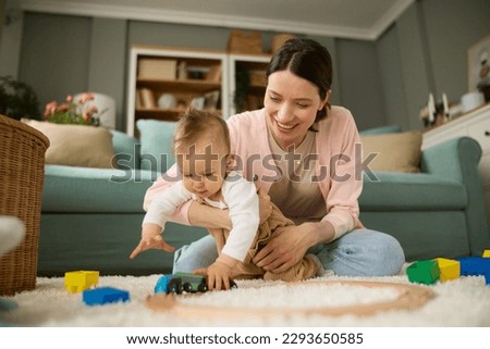 Joyful mother and baby boy playing with toys on a carpet at home Royalty-Free Stock Photo #2293650585
