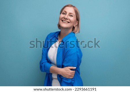 close-up of a cute mature woman in a shirt on a blue background with copyspace